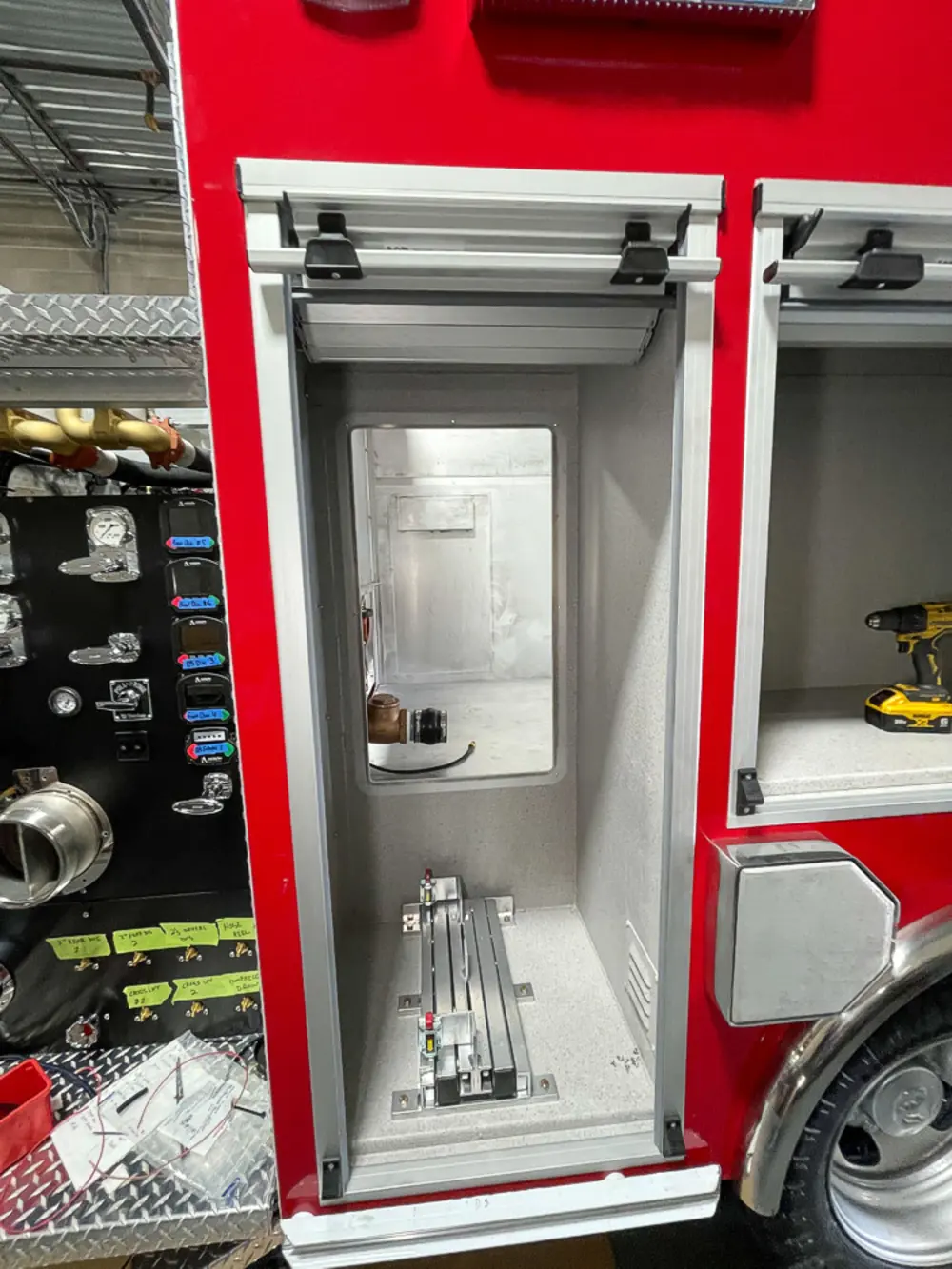 Exterior view of small fire truck showing cab, body compartments, and wheel/tire area.